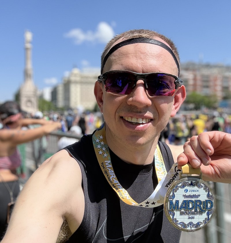 Holding up the Madrid Marathon 2025 medal at Plaza de Colón.