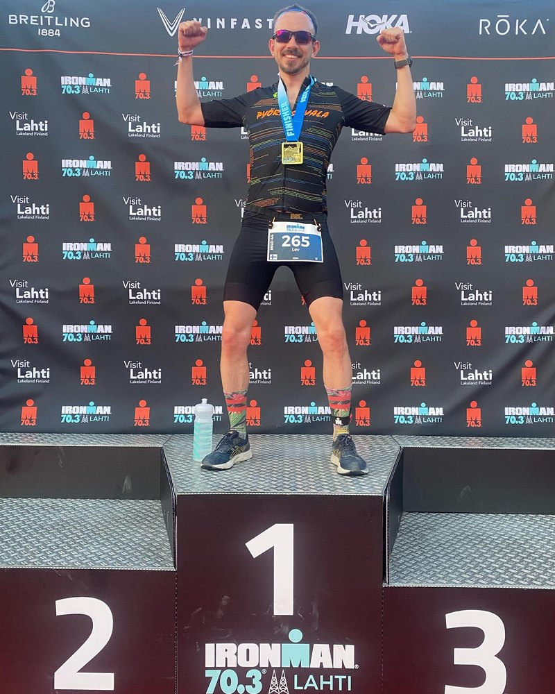 On the IRONMAN 70.3 Lahti 2024 finish photo platform, fists raised.